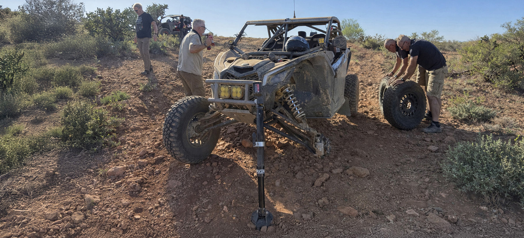Can-Am X3 being worked on by people in a desert setting with AGM Electric Jack PRO